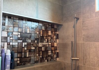 Close-up van regendouche met decoratieve nis en wandtegels in natuurtinten, in moderne badkamer in Bergen op Zoom